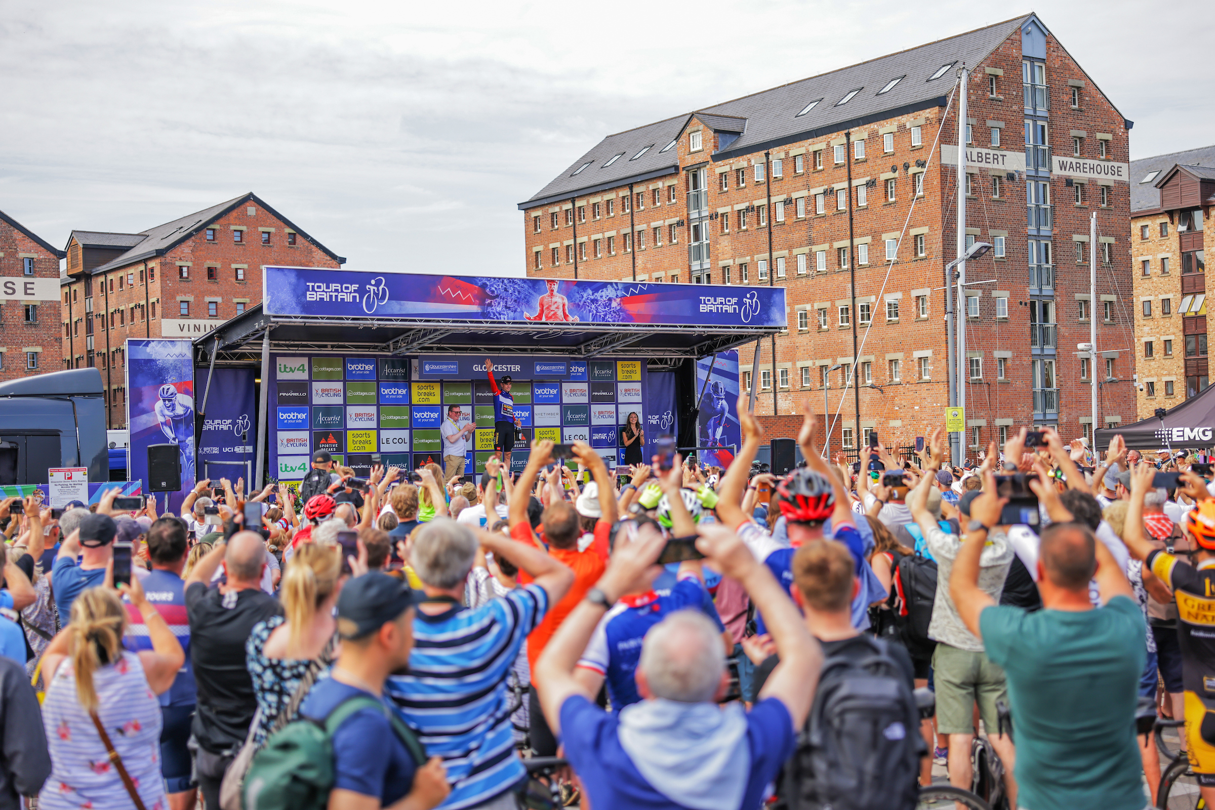 Crowds cheer on Wout van Aert on the podium at the finish in Gloucester