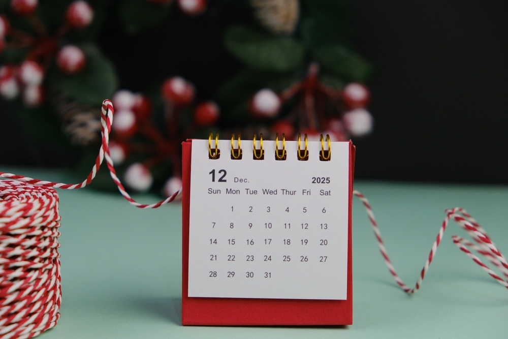 A white stand up calendar on a red background showing dates for December 2025