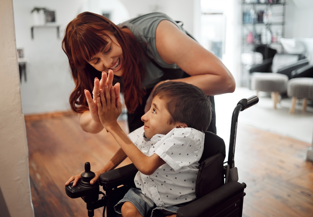 Young person in wheelchair giving a high five to an adult