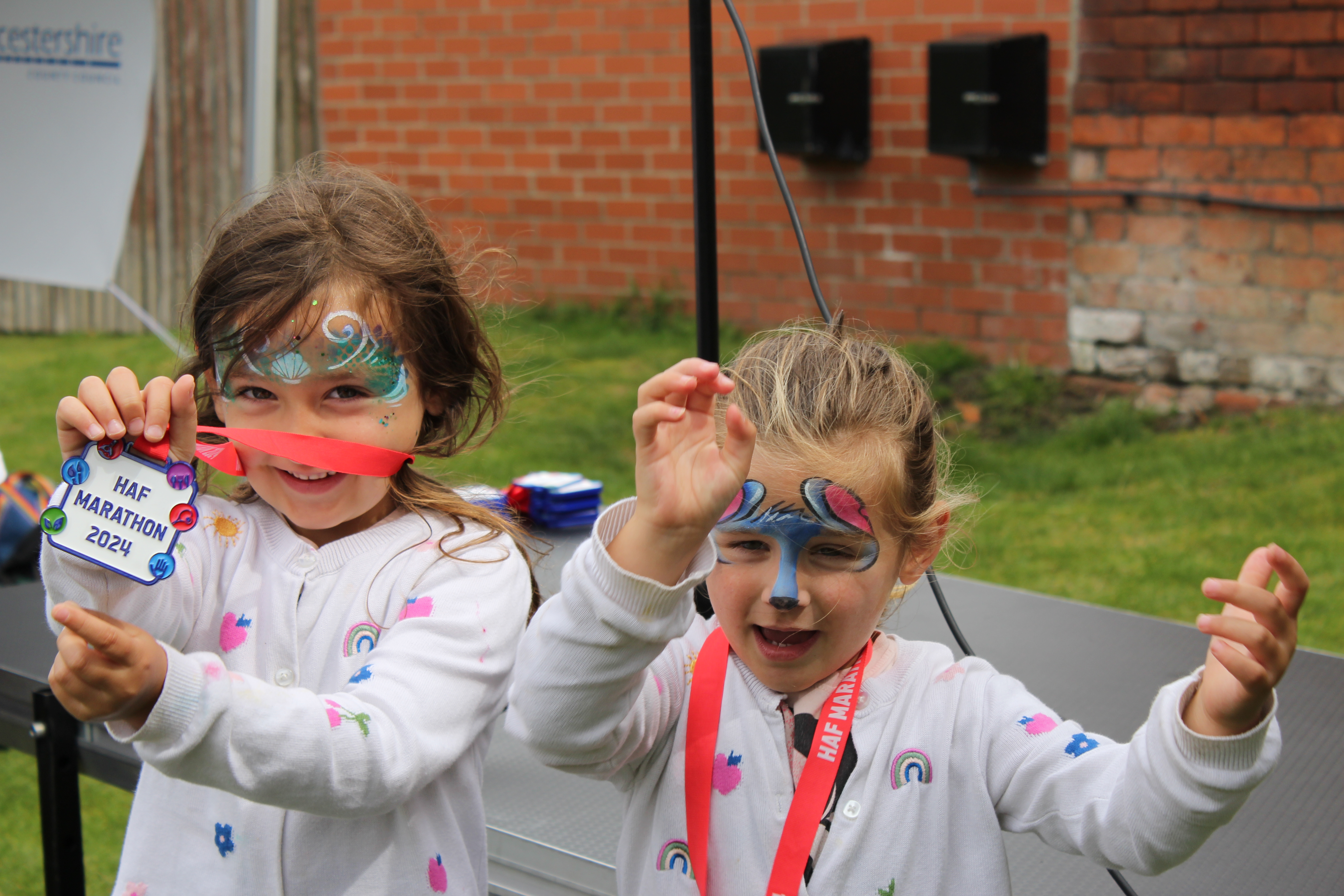 two happy children wearing facepaint show their HAF medals