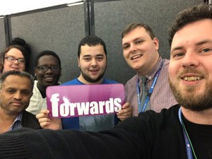 Group of people taking a selfie and holding the forwards logo.