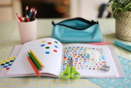 A school book with scissors and coloured pencils