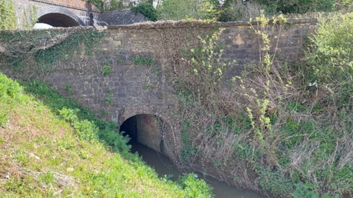 Photo of the stone bridge from the grassy lower river bank