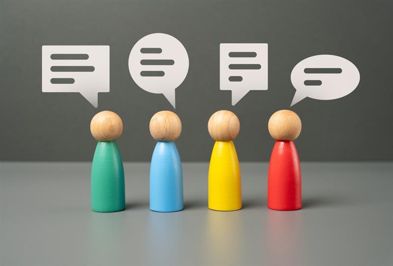 Four colourful wooden figurines with blank speech bubbles