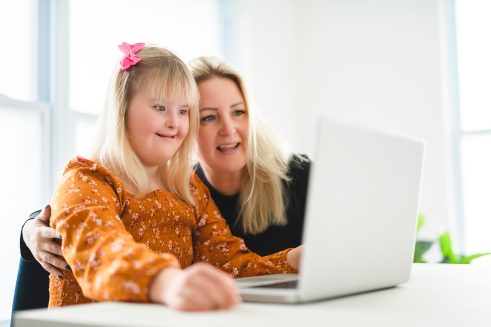 Woman and little girl smiling and looking at laptop screen