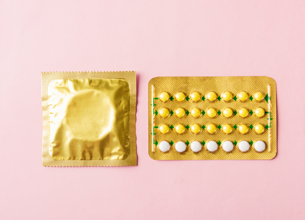 Picture of condom and Pre-Ep in golden packets on a pink background