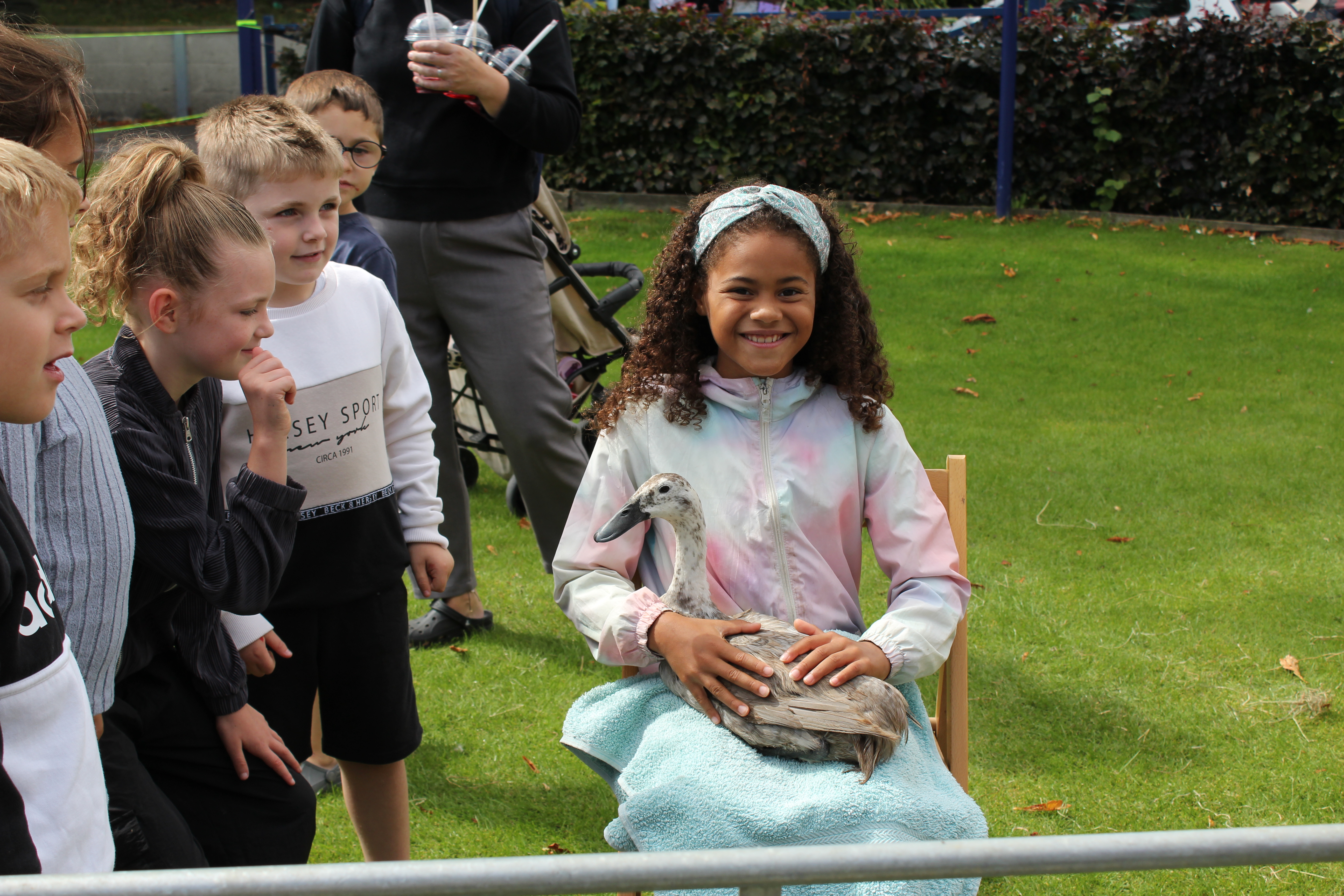 Smiling child holds a goose with other children nearby