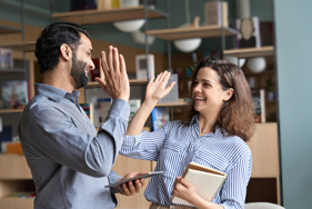 A man an a women in work attire high fiving each other.