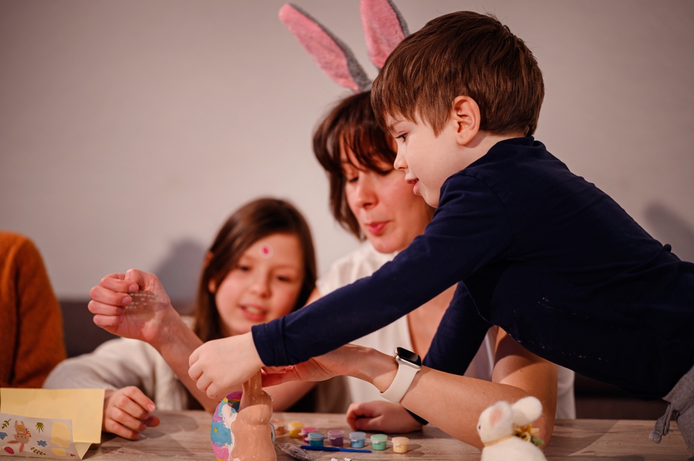 Woman supporting two primary-aged children with Springtime crafting