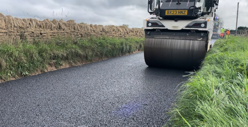 Photo of roller vehicle driving on freshly laid asphalt