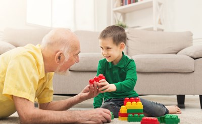 Older Carer And Young Boy With Colourful Blocks