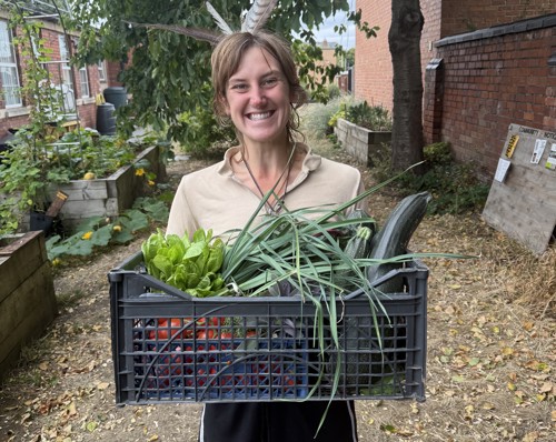 Green Pledge Project Officer Hannah with a basket of veg in the Hub Community Garden.