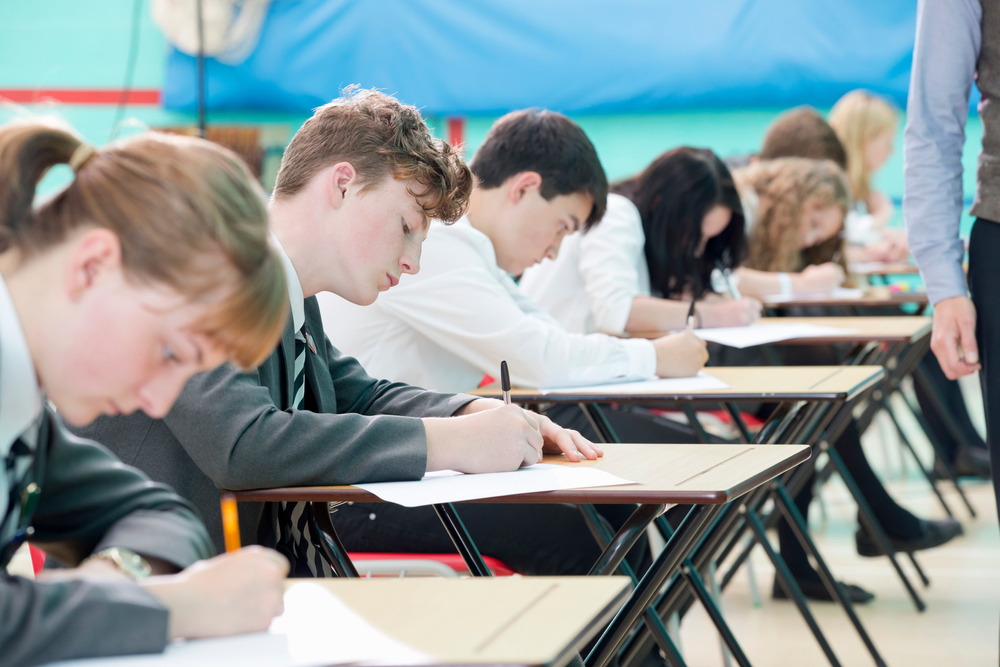Close up of focused students taking examination at desks. 