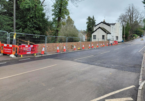 Photo of open road with fencing and traffic cones on pavement