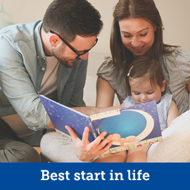 A man and woman reading a book to a child
