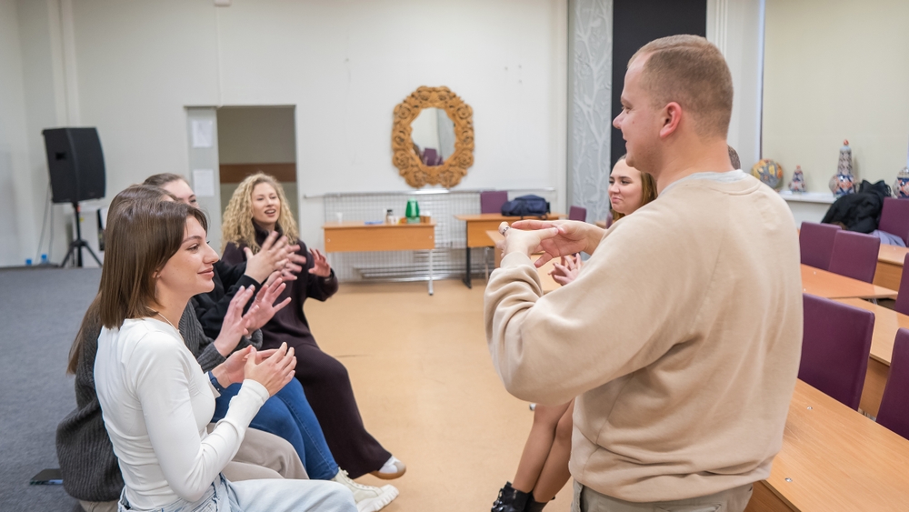 Six students and lecturer communicate in a seminar room at a university.