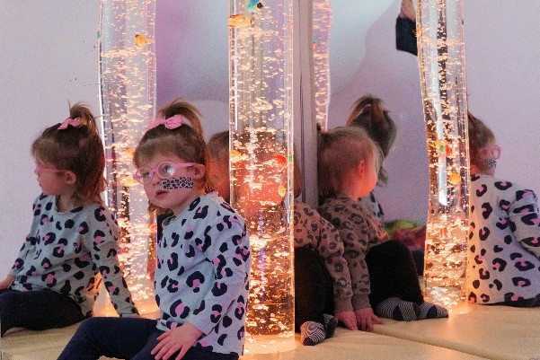 Two young girls with glasses sitting next to a bubble column and a mirrored wall