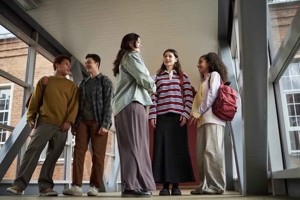 Group of 5 college students chatting outside classroom 