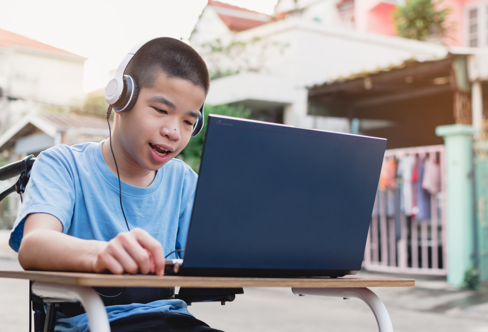 Child in wheelchair wearing headphones and using a digital device