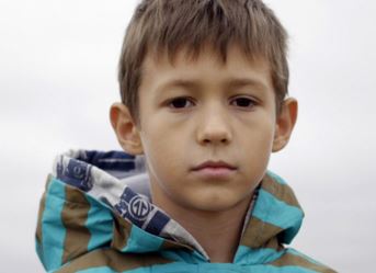 Unaccompanied boy looks at camera