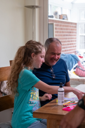 Image of Chloe sitting down with an adult at a table involved in a arts and crafts activity