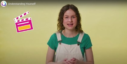 Screenshot from a film of a young person talking about Autism wearing a green t-shirt and white dungarees with an icon of a clapper board