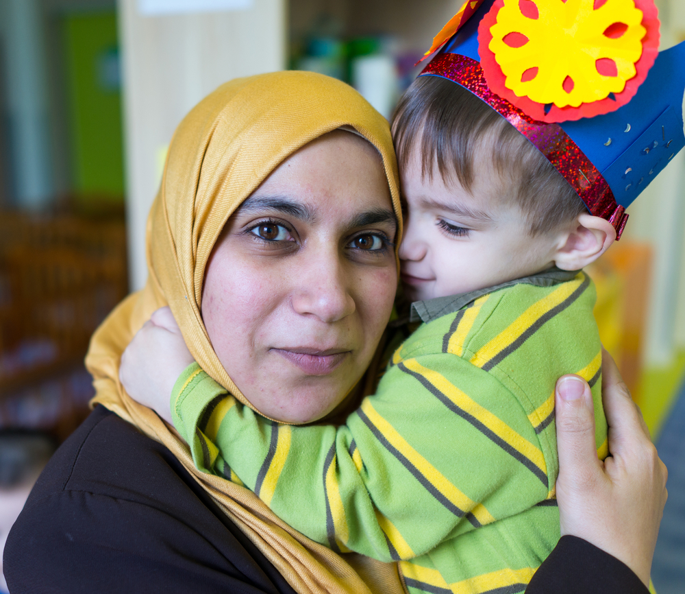 Woman and young child - wearing a paper crown - in embrace