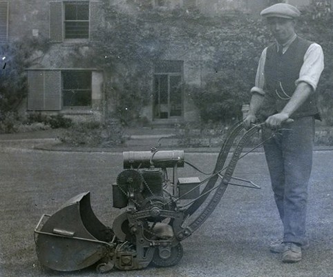 An image of a man using an old lawnmower